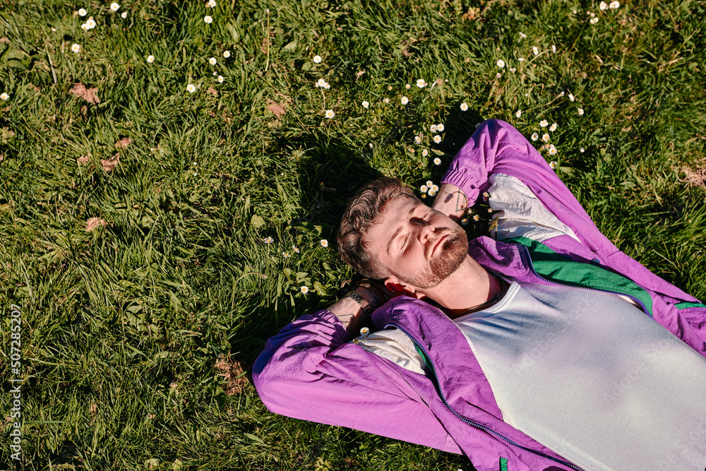 Young blond man lying on a green meadow with a relaxed expression on his face with copyspace Young blond man lying on a green meadow with a relaxed expression on his face with copyspace
