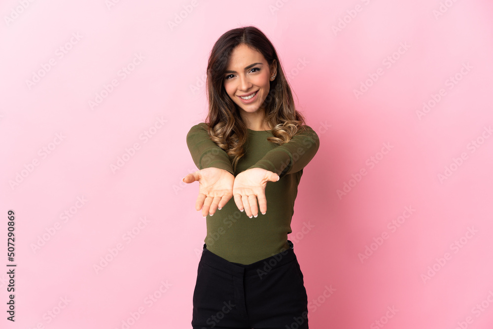 Young caucasian woman isolated on pink background holding copyspace imaginary on the palm to insert an ad Young caucasian woman isolated on pink background holding copyspace imaginary on the palm to insert an ad