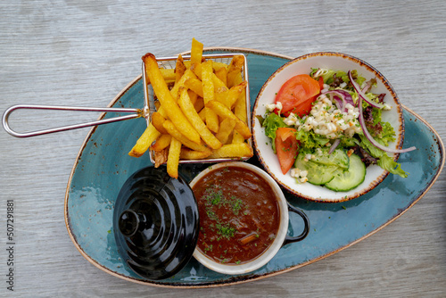 Top view of sour meat (Dutch: Zuurvlees) served with french fries (friet or patat ) and mixed salad, Is a regional meat dish from Limburg, Province that exists in both the Netherlands and Belgium. photo