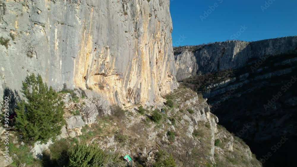 AERIAL: Flying close to sunlit climbing wall and approaching female rock climber. Adrenaline outdoor activity in beautiful and picturesque environment. Rock climber on the way up of limestone wall. AERIAL: Flying close to sunlit climbing wall and approaching female rock climber. Adrenaline outdoor activity in beautiful and picturesque environment. Rock climber on the way up of limestone wall.