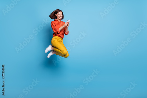 Full size profile side photo of young lady use mobile jump energetic share app button download isolated over blue color background