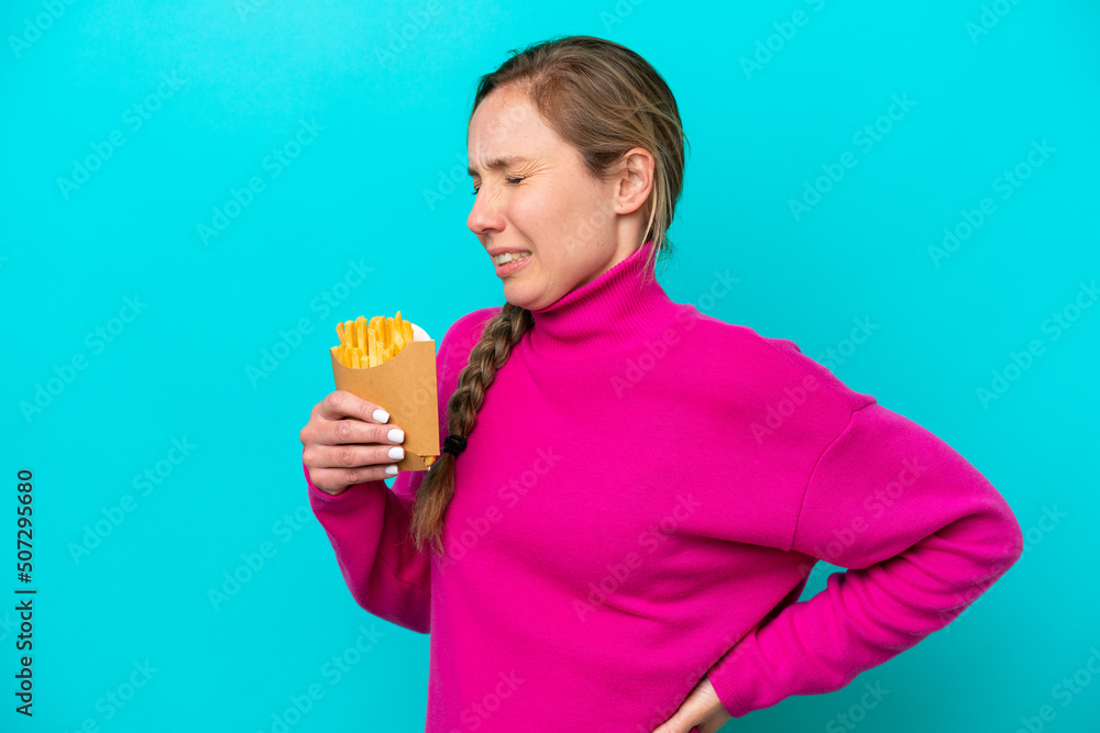 Young caucasian woman holding fried chips isolated on blue background suffering from backache for having made an effort Young caucasian woman holding fried chips isolated on blue background suffering from backache for having made an effort