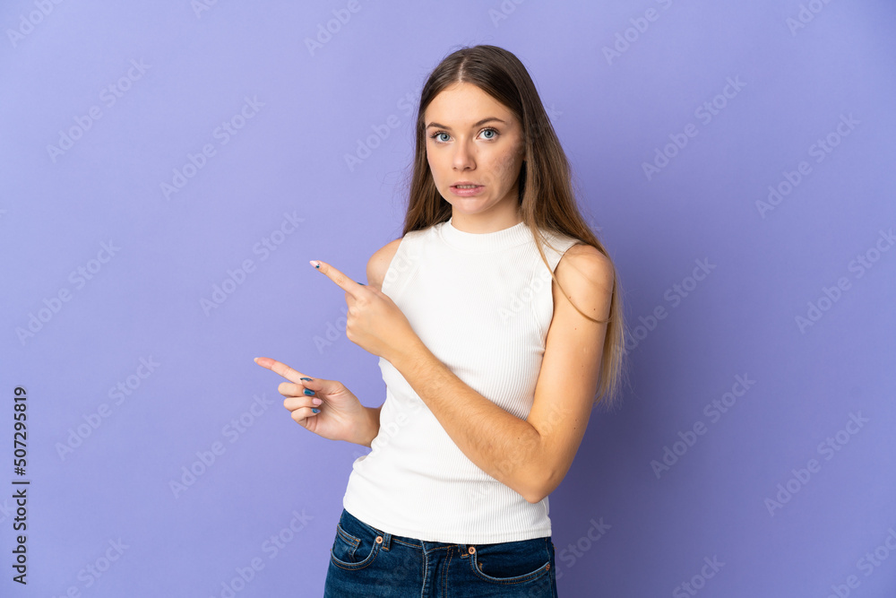 Young Lithuanian woman isolated on purple background frightened and pointing to the side Young Lithuanian woman isolated on purple background frightened and pointing to the side