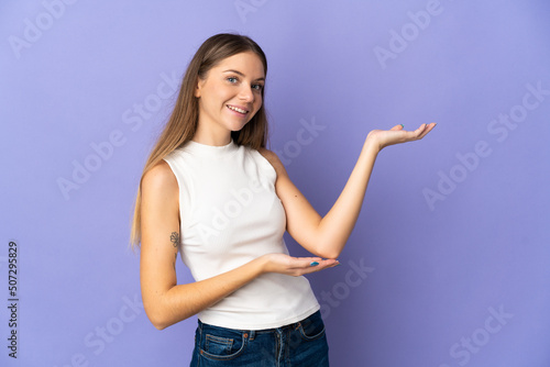 Young Lithuanian woman isolated on purple background extending hands to the side for inviting to come