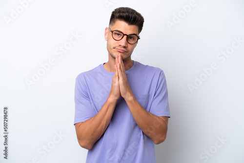 Young caucasian man isolated on white background keeps palm together. Person asks for something © luismolinero