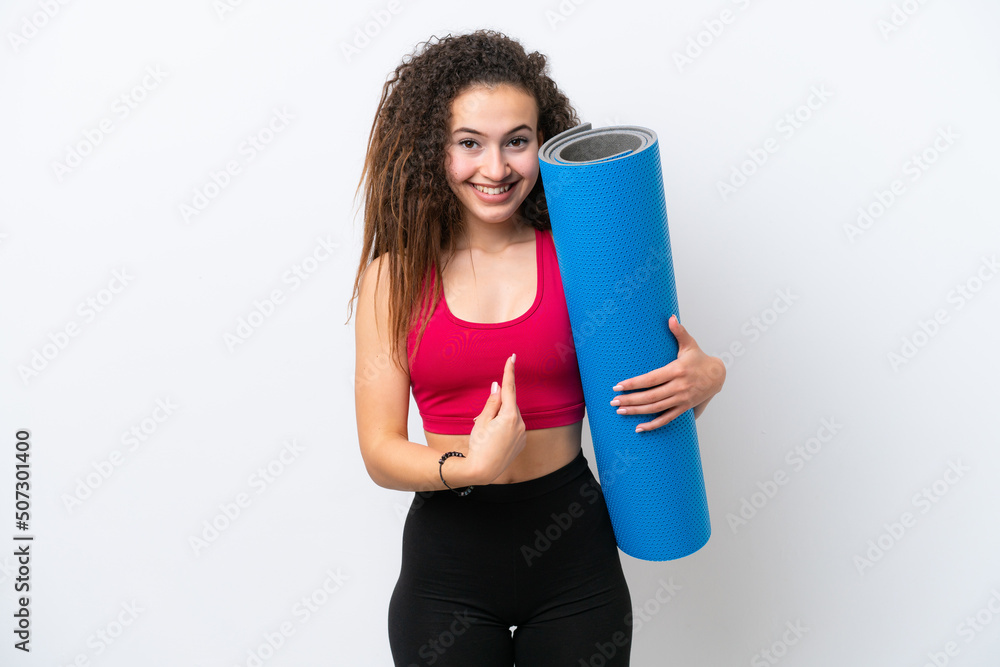 Young sport Arab woman going to yoga classes while holding a mat isolated on white background with surprise facial expression