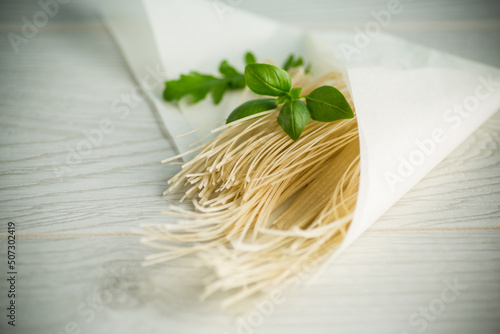 homemade thin dried egg noodles in paper bag with basil