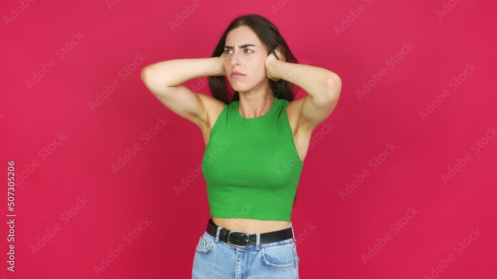 Young brunette woman covering both ears with hands. Frustrated expression over isolated background Young brunette woman covering both ears with hands. Frustrated expression over isolated background