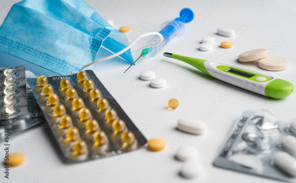 Sickness medicine pills face mask vitamine injection thermometer on white background in photo studio Sickness medicine pills face mask vitamine injection thermometer on white background in photo studio
