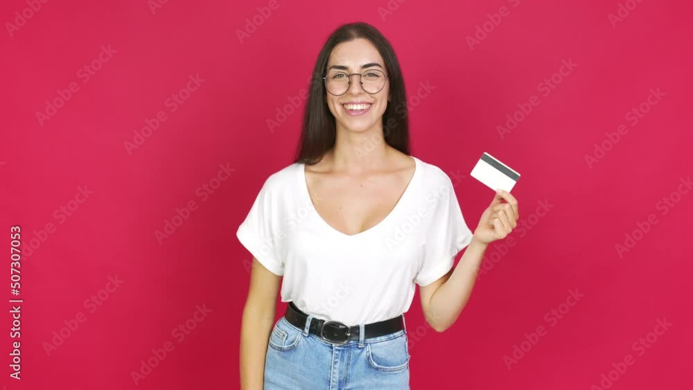 Young brunette woman happy and holding a credit card over isolated background Young brunette woman happy and holding a credit card over isolated background