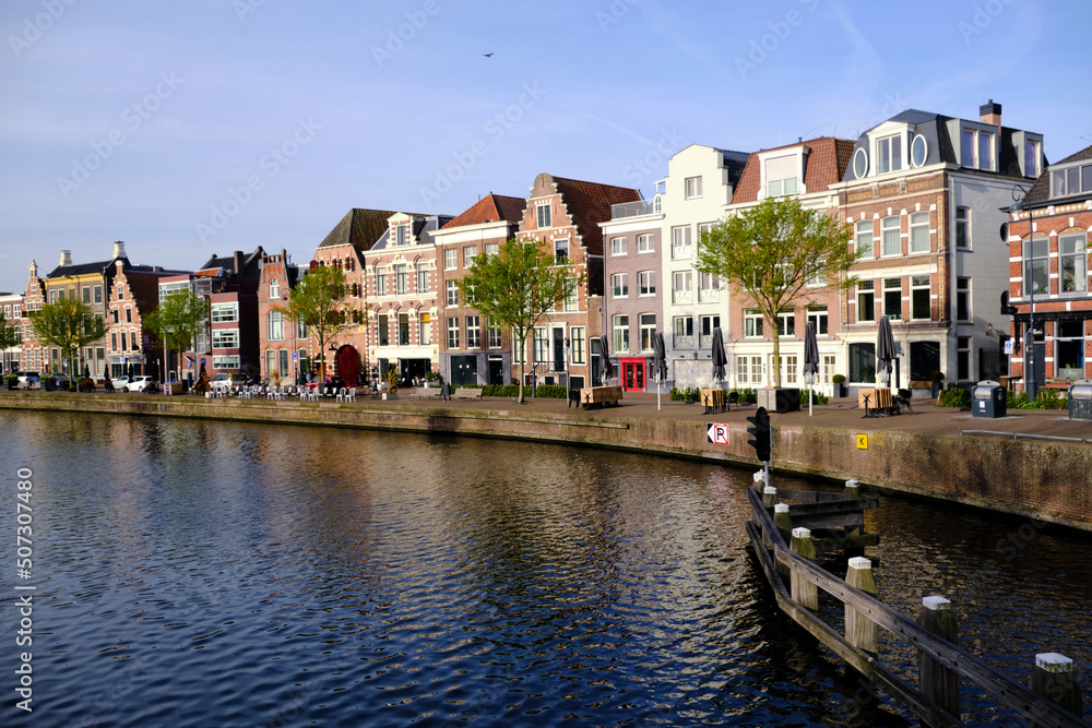 Haarlem, Netherlands - April 12. 2022: Traditional Dutch houses lining the river Sparne viewed from the Melkbrug bridge in springtime.