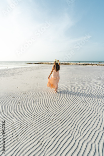 young hispanic woman with dress and hat on a beach with textured sand photo