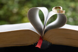 A pair of wedding rings over a heart made with  leaves from the Bible