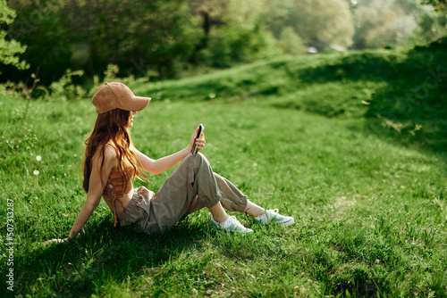 Freelance woman working on her phone against a green summer landscape, the lifestyle of a blogger photo