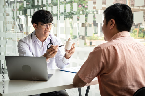 Male doctor discussing with the patient explaining symptoms of the disease after diagnosis checking while recommending treatment methods in clinic
