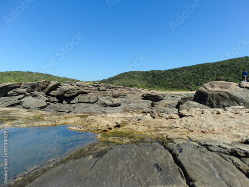 Linda praia com grandes pedras, banhada pelas ondas do mar, formando assim uma picina, céu azul e linda paisagem ao fundo fotografado em Vitória no estado do Espírito Santo, Brasil. photo
