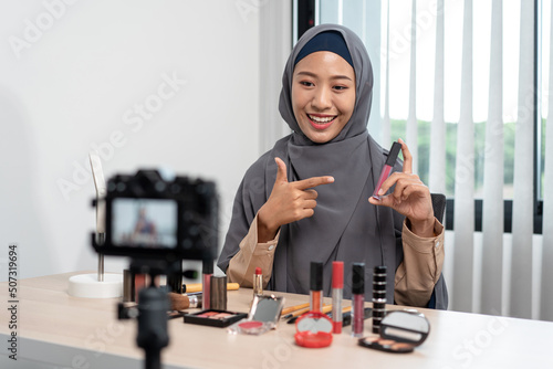 Woman muslim blogger is showing present make up tutorial beauty cosmetic review product and broadcast live streaming video to social network teaching online on the camera screen