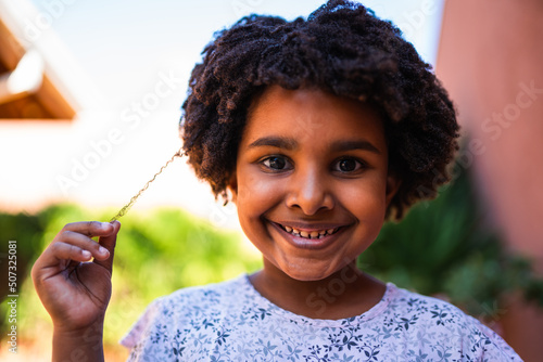 Sorridente criança puxando seu cabelo com as pontas dos dedos