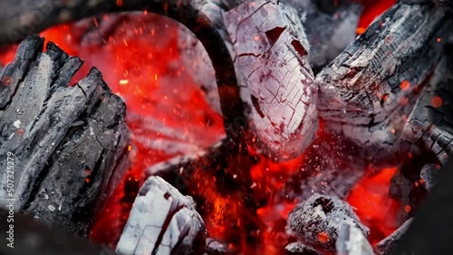 close-up of a very hot coal burning on a grill in slow motion and flames. Smoldering coal, fiery background, red flame burns out photo