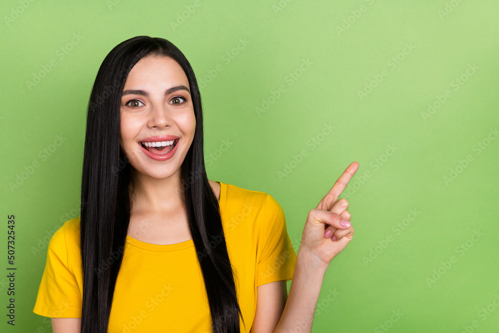 Photo of impressed funny woman wear yellow t-shirt pointing empty space isolated green color background Photo of impressed funny woman wear yellow t-shirt pointing empty space isolated green color background
