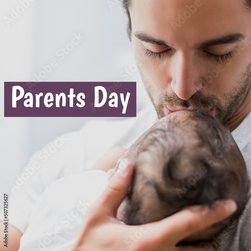 Parents day text with young caucasian father kissing forehead of baby