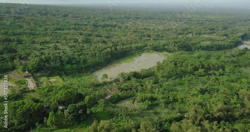 Aerial flight over lake result of volcanic sand mining surrounded by green jungle of Indonesia during sunny day misty day. It located on the slope of Merapi Volcano, Cebtral Java, Indonesia photo