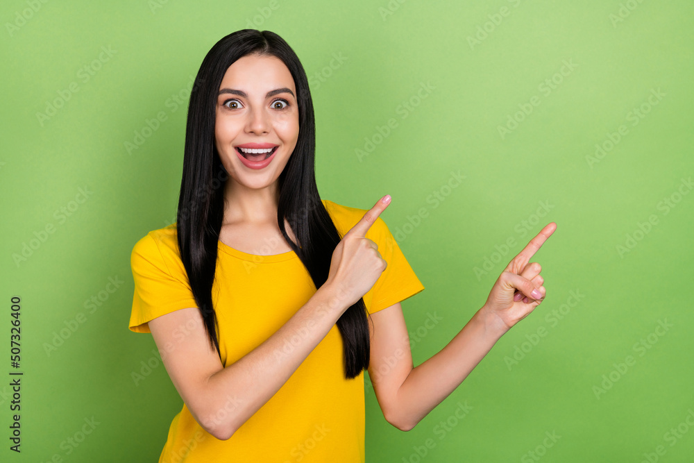 Photo of cute excited lady dressed yellow t-shirt open mouth pointing empty space isolated green color background Photo of cute excited lady dressed yellow t-shirt open mouth pointing empty space isolated green color background