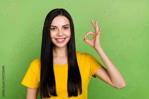 Photo of sweet cute woman wear yellow t-shirt showing okey sign isolated green color background