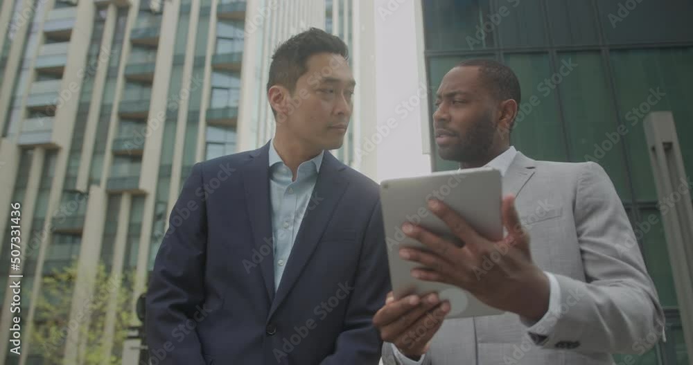 Business Men Meeting Outdoors using Digital tablet Technology on Street Business Men Meeting Outdoors using Digital tablet Technology on Street