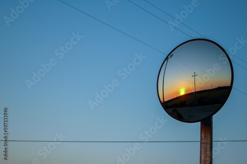spectacular sunset reflected in a circular mirror placed on a telephone pole photo