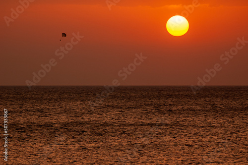 a tourist practicing parasailing on an Ibiza beach at sunset