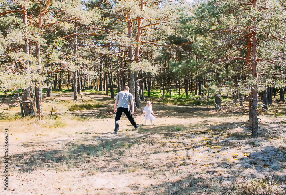 Fototapeta premium Father and daughter playing in a spring forest. Active people are having a good time outdoors