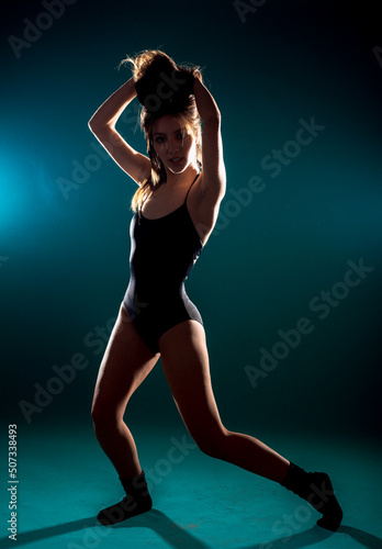 Dancer practicing modern dance while standing against cyan background © qunica.com