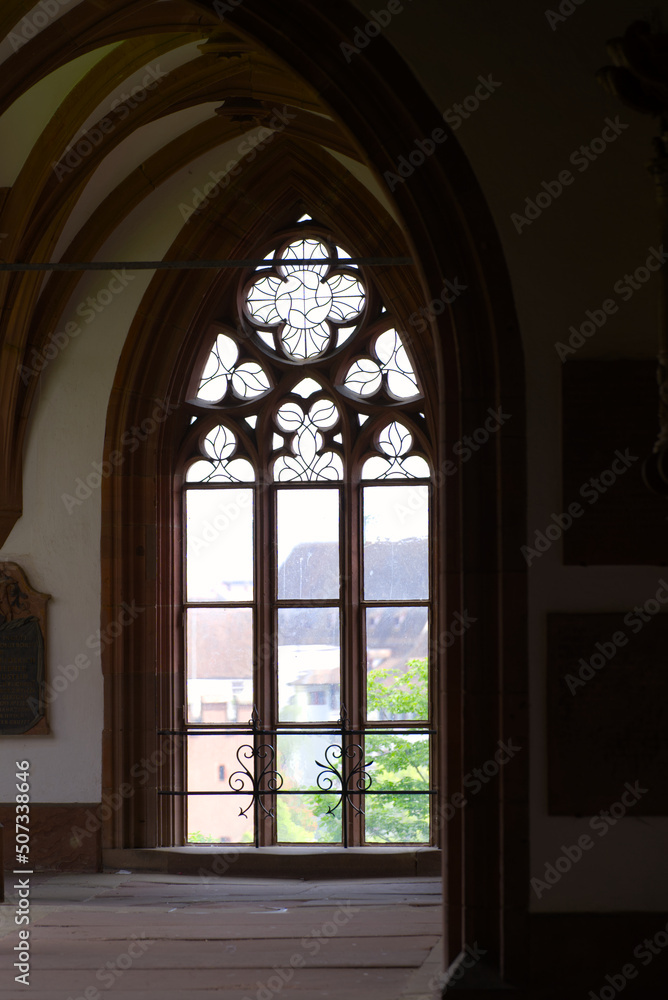 Beautiful window at cloister of Basler Minster at the old town built with red sandstone on a blue cloud spring day. Photo taken April 27th, 2022, Basel, Switzerland.