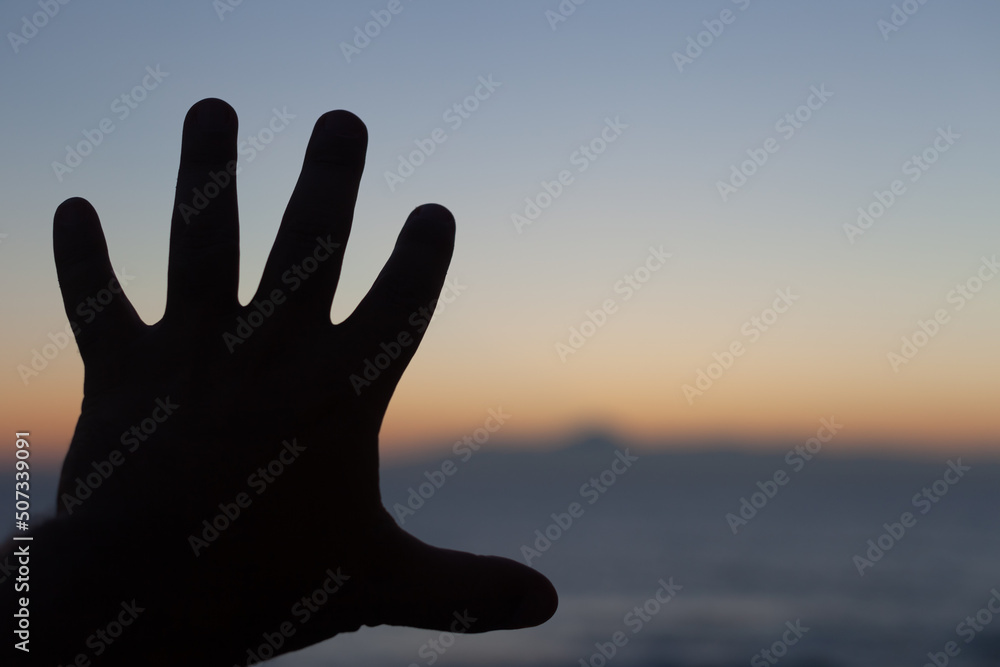 close up of the silhouette of a hand at sunset