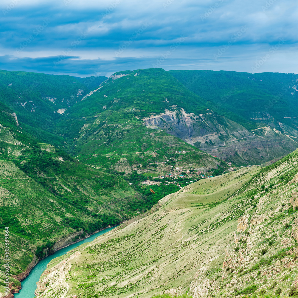 Mountain landscape in the Caucasus in Dagestan, view of the canyon of the Sulak River with the village of Old Zubutli in the distance on the slope; visible soaring vulture