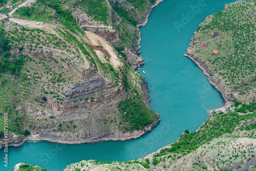 mountain landscape with a deep canyon with a blue river along which a motor boats moves photo