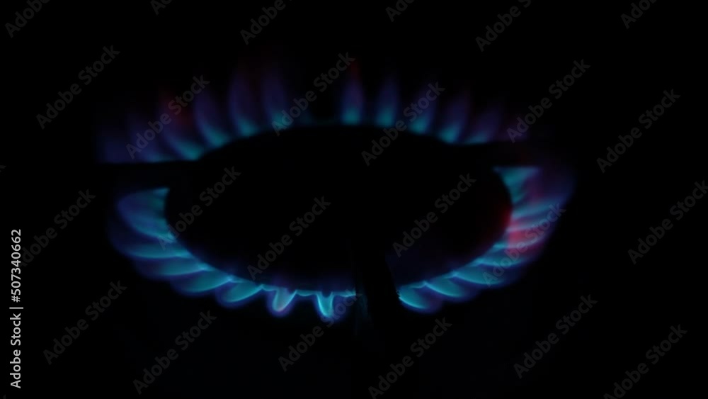 the gas burner on the kitchen stove lights up. Burning blue flame of fire in the dark on a black background. Inflammation of natural gas. Natural energy carrier, fossil fuel the gas burner on the kitchen stove lights up. Burning blue flame of fire in the dark on a black background. Inflammation of natural gas. Natural energy carrier, fossil fuel
