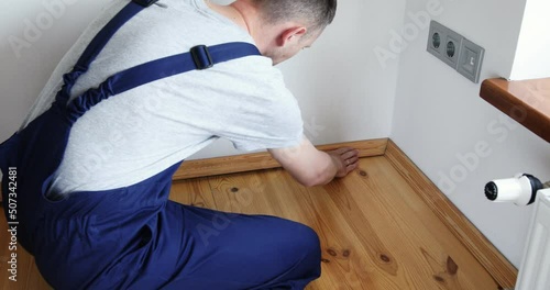 To make repairs. Installing a new skirting board. a man makes repairs in a room
