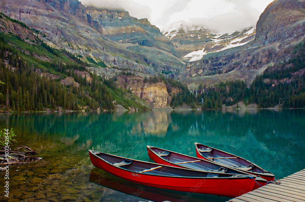 Lake O'Hara in British Columbia with three red canoes on a calm morning