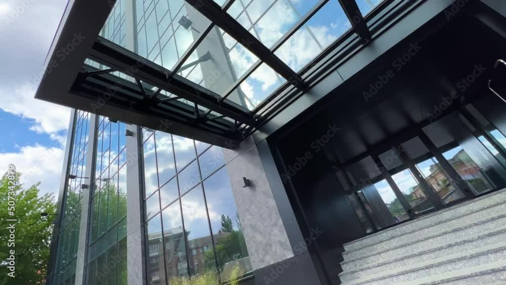 Glass office facade of a skyscraper with entrance. Low wide angle view. Dutch angle Glass office facade of a skyscraper with entrance. Low wide angle view. Dutch angle
