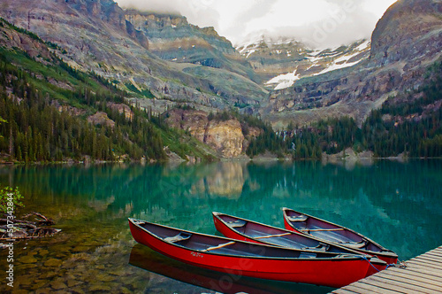 Lake O'Hara in British Columbia with three red canoes on a calm morning