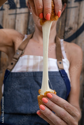 Finger food. Caucasian woman chef stretching fried mozzarella cheese sticks.	
