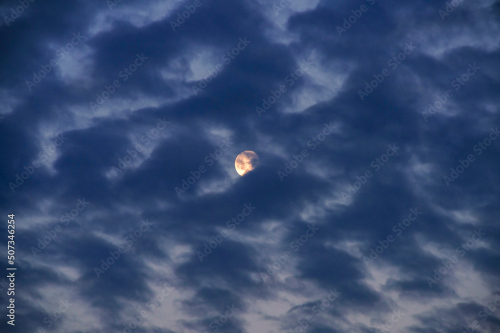 Full moon partly covered with altocumulus clouds, just before the sunrise, almost dawn - obrazy, fototapety, plakaty 