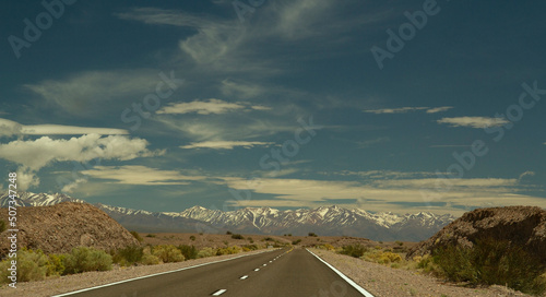 Traveling along the asphalt highway across the arid desert and into the Andes cordillera, under a beautiful blue sky with clouds.  photo