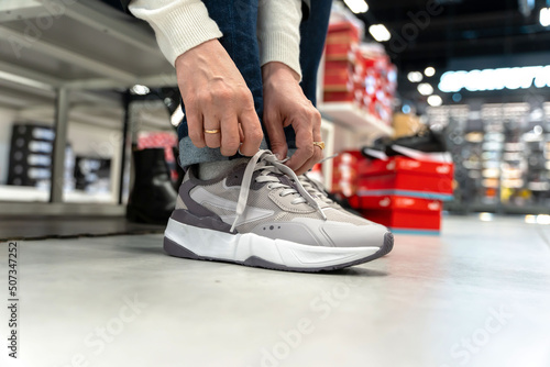 a girl tries on new sneakers in a sportswear store  © Андрей Знаменский