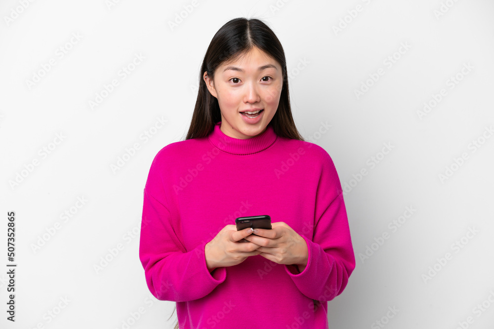 Young Chinese woman isolated on white background surprised and sending a message Young Chinese woman isolated on white background surprised and sending a message