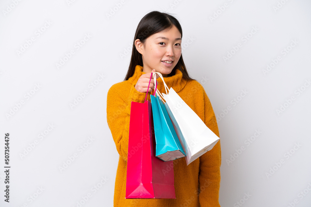 Young Chinese woman isolated on white background holding shopping bags and smiling Young Chinese woman isolated on white background holding shopping bags and smiling
