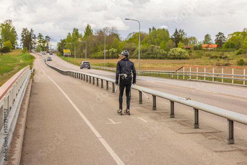 Man trains on roller skis on dedicated bike path on summer day. Concept of sports  healthy lifestyle. Sweden.