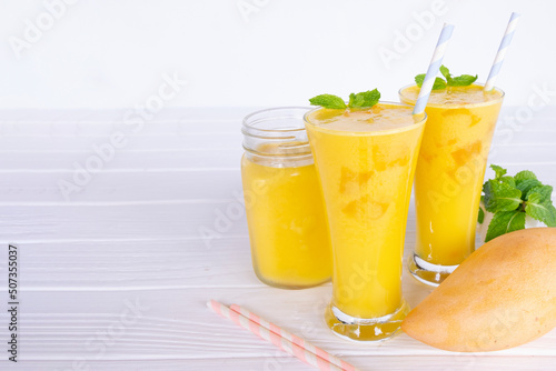 Mango smoothies yellow colorful fruit juice milkshake blend beverage healthy high protein the taste yummy In glass,drink to lose weight drink episode morning on white gray background.